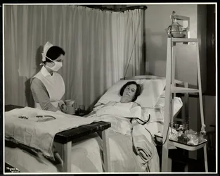Eine maskierte Krankenschwester mit einem Patienten in einem Raum im Sloane Medical Hospital, Broadway und 168th Street, New York, 1932